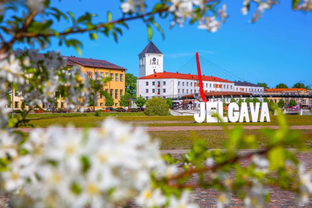 Attēlā var redzēt Jelgavas gājēju tiltu un pilsētas nosaukuma uzrakstu